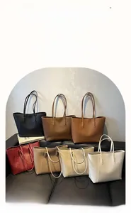 Minimalist large tote bags displayed in seven neutral colors on a leather sofa
