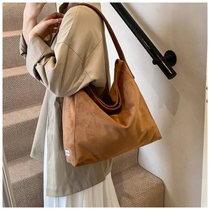 Detail of a large brown suede tote bag styled with an earthy minimalist outfit on stairs