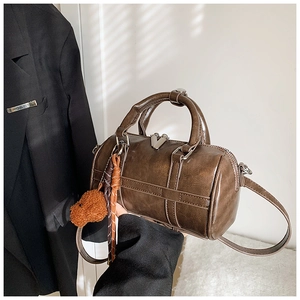 Détails du sac Boston marron avec finitions cousues et pendentif ours en peluche
