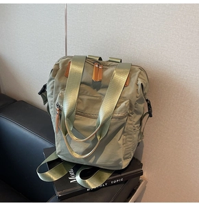Detail of sage green nylon backpack with brown leather accents and side buckle straps