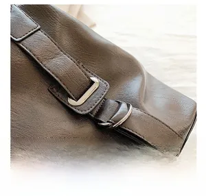Detailed close-up of dark brown leather bag showing silver buckle and precision stitching