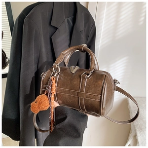 Détail d'un sac Boston en cuir marron avec un pendentif ours en peluche texturé