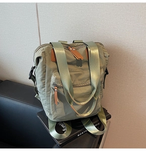 Olive green nylon backpack detail with leather pullers and multi-pocket design