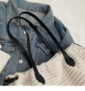 Detail of white faux shearling tote bag featuring black strap and drawstring closure
