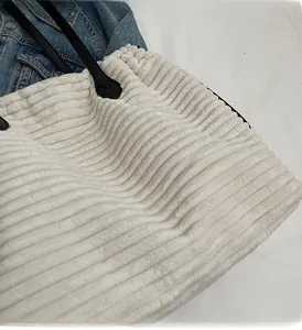 Detail view of beige corduroy tote bag featuring black slim leather straps and soft texture