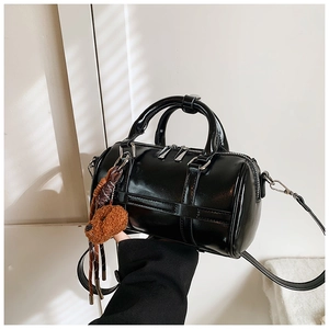 Détail du sac Boston noir brillant avec doubles anses et un joli charm d'ourson
