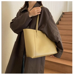 Minimalist mustard yellow tote bag shown on model with dark brown trench coat