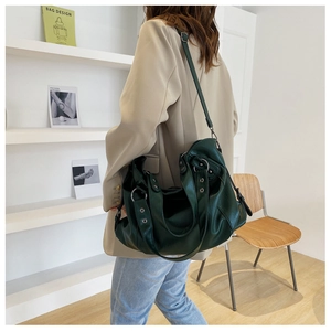 Detail of dark green leather tote bag worn by model in a minimalist modern interior