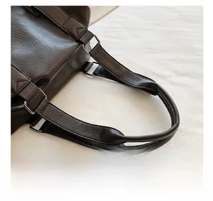 Close-up of pebble-textured leather tote bag handles with silver-tone metal ring connectors