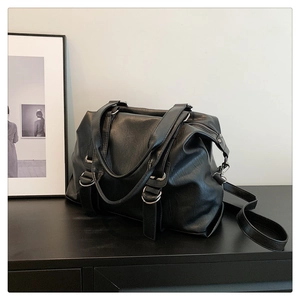 Close-up of a black textured leather tote bag with silver hardware on a dark surface