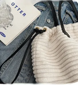 Detail of white corduroy tote bag showing drawstring closure and black handles
