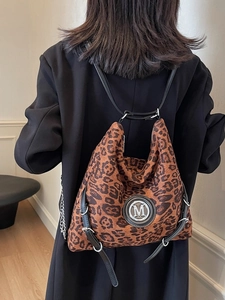 Retro-Rucksack mit Leopardenmuster, silbernes M-Logo, präsentiert auf schwarzem Anzug