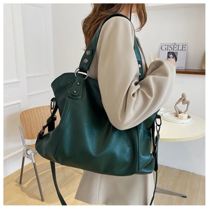 Detail of dark green leather tote bag featuring metallic hardware and pleated side design
