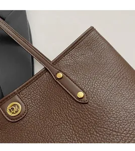 Detail of brown lychee grain leather tote bag with DM logo and manual stitching accents