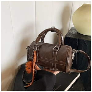 Détail du sac Boston marron foncé avec breloque ours en peluche et bandoulière