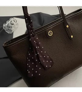Close-up of dark brown lychee grain leather tote bag with gold logo and polka dot scarf