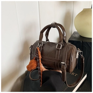 Détail du sac Boston vintage marron avec pompon décoratif et finitions en corde tressée