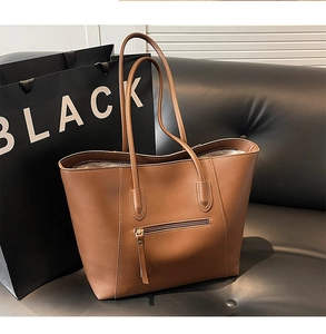 Detail of brown faux leather tote bag showing back zipper pocket and fine stitching