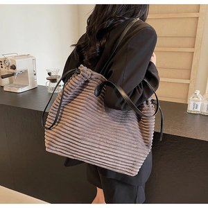 Detail of grey corduroy tote bag with drawstring closure and slim leather straps