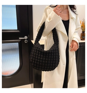 Detail of black quilted bubble shoulder bag with a textured puffy design on model
