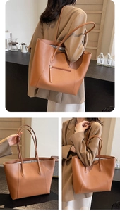 Macro detail of brown leather tote bag showing fine texture and front zipper pocket