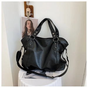 Detail of a black large-capacity tote bag with silver studs and adjustable strap