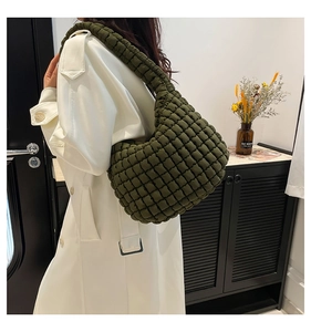 Macro shot of olive green quilted bubble tote bag with detailed woven texture on the strap