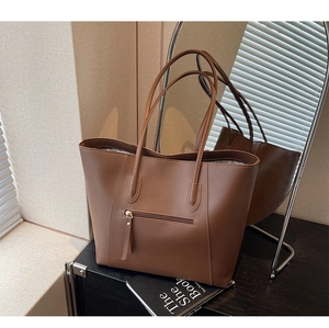 Detail view of a brown leather tote bag with functional exterior zipper pocket