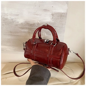 Détail du sac Boston en cuir ciré bordeaux avec doubles poignées et fermeture éclair argentée