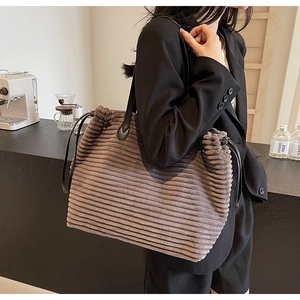 Detail of vintage brown corduroy tote bag with black leather straps and pleated top edge