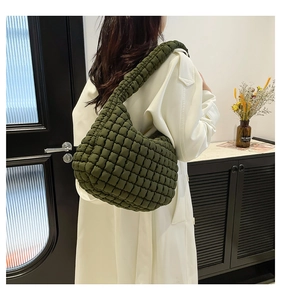 Detail of army green quilted shoulder bag with puffy texture worn by model in trench coat