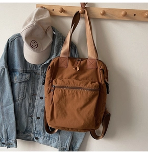Close-up of caramel brown tote backpack with reinforced handles and durable canvas texture