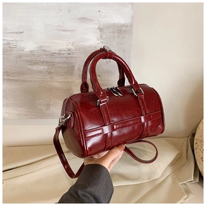 Détail du sac Boston rouge foncé avec texture polie, fermetures éclair et anses en cuir