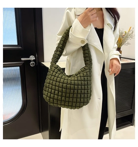 Close-up of olive green quilted cloud bag with textured pleats worn by a model