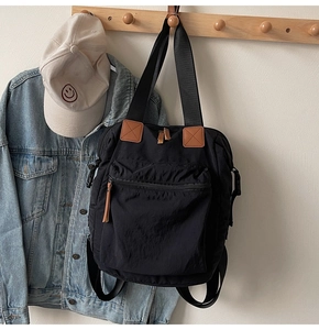 Detail of black convertible tote backpack with brown leather pulls and large zipper pocket
