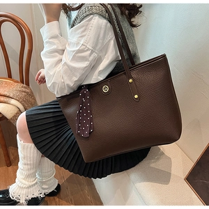 Detail of dark brown lychee leather tote bag featuring elegant polka dot silk scarf detail