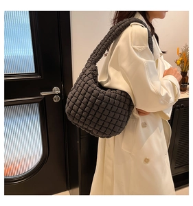Close-up of dark grey quilted shoulder bag with soft bubble texture and padded nylon