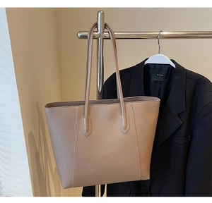 Detail view of large beige leather tote bag with dual straps and decorative stitching