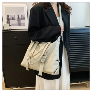 Detail of a large cream tote bag with metal ring accents and smooth PU leather texture