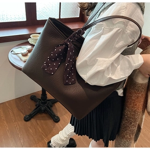 Close-up of brown litchi leather tote bag with a polka dot silk scarf on the handle