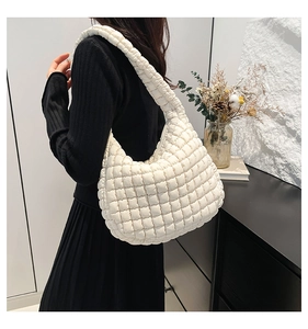 Detailed back view of a beige quilted bucket bag styled with a minimalist black outfit