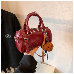 Détail du sac Boston rouge foncé brillant avec finitions argentées et breloque chien