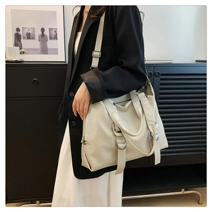 Detail view of large cream tote bag with adjustable shoulder strap and metallic D-ring