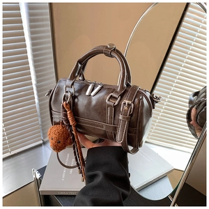 Détail du sac Boston vintage marron foncé avec charm ours et lanières en cuir