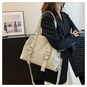Urban style cream tote bag with silver metal rings worn by a model in a minimalist setting