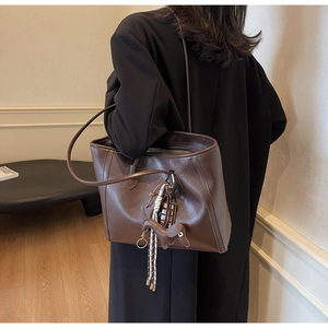 Detail of dark brown matte leather tote bag with cute puppy charm on a shoulder strap