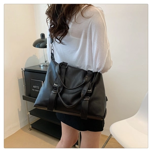 Rear view of a black oversized tote bag with adjustable straps in a modern room