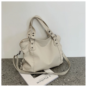 Detailed side view of cream PU leather bucket bag with silver studs and long shoulder strap