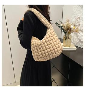 Detail of beige quilted bubble bucket bag with soft shoulder strap and textured fabric