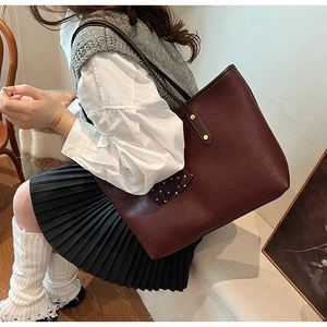 Detail of burgundy lychee grain leather tote bag with a polka dot bow accessory